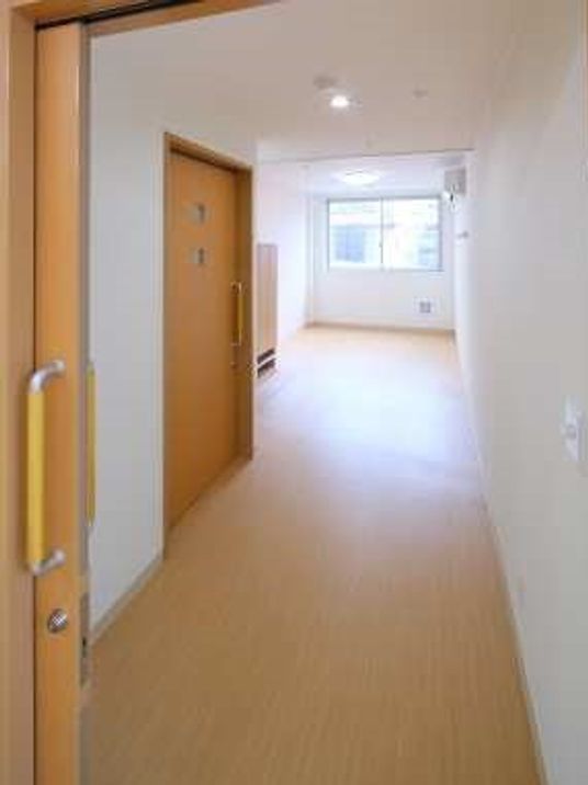 フローリング仕様の床がまっすぐに続く居室内。手前の引き戸、奥のほうにトイレのドアが見えている様子