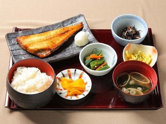トレーには冬季の皿が並んでいて、魚の干物や野菜の和え物、ご飯やみそ汁が盛られている。