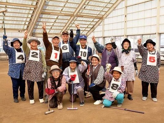 グランドゴルフ場で元気に集合写真を撮る入居者の様子。