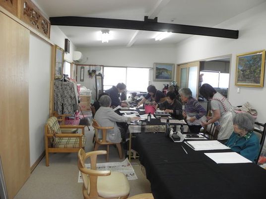 テーブルを囲み、書道教室に励んでいる入居者。壁には絵画が飾られている。