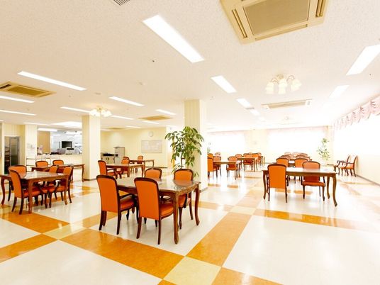 四人掛けのテーブルと椅子が並べられている施設の食堂の様子