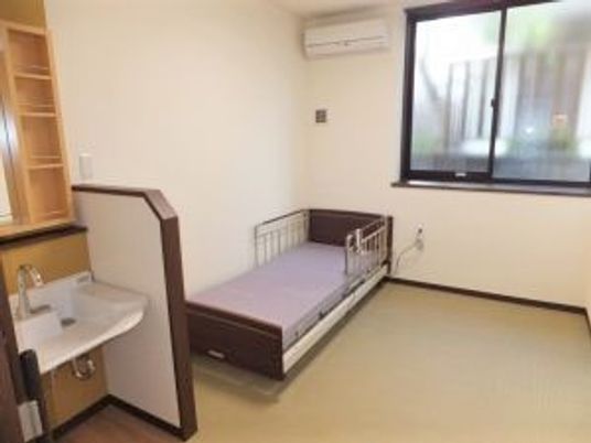 パーテンションで洗面所とベッドが区切られ、エアコンも設置された一人部屋。