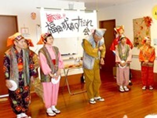 地域ボランティアの人たちがすだれを見せてくれるステージ。作務衣を着た男女が並んで立っている。