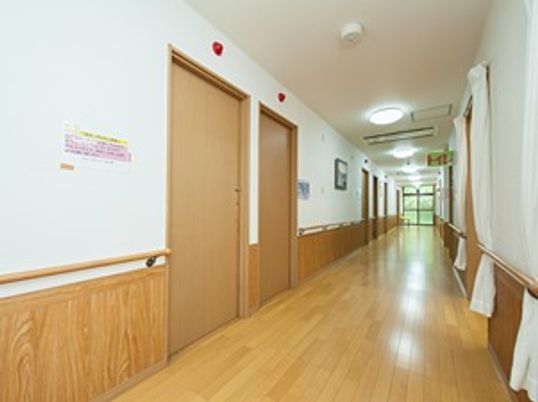 手すり付きの長い廊下と両側の個室の様子。照明があるのが分かる