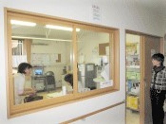 ヘルパーステーションには白衣を着たスタッフがいて、ドアのところに立っている女性と話をしている。