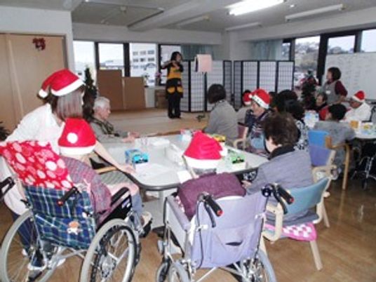 赤いサンタ帽をかぶってクリスマス会に参加している入居者とスタッフ。