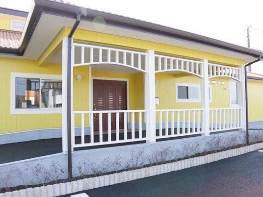 黄色い外壁の明るい雰囲気の建物の玄関には大きな屋根が付き、車の行き来もできる。ゆるやかなスロープも付いている。