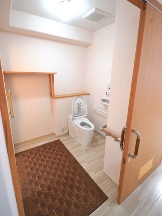 広々としたトイレにはブラウンのマットが敷かれ、手すりや呼び出しボタンが付いている。