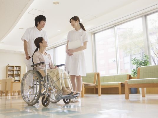 建物の中で話している看護師と医師、患者。明るい日差しが差し込んでいる様子