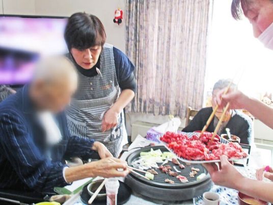 焼き肉を楽しむ施設内の高齢者とスタッフの様子。食事の風景
