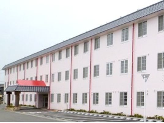 3階建ての建物は薄いピンクで玄関には大きな車寄せも付いていて、駐車場もある。