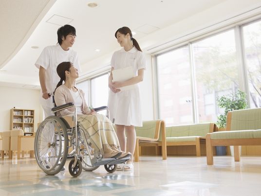 建物の中で話している看護師と医師、患者。明るい日差しが差し込んでいる様子