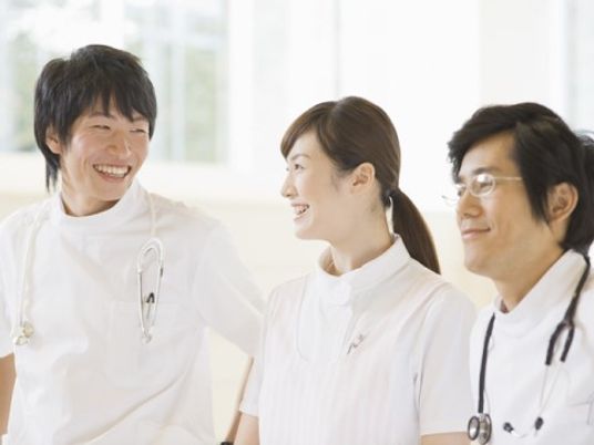 ミーティング中らしき医療関係者の様子。やわらかい表情で微笑んでいる様子。
