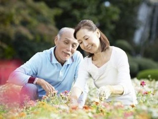 夫婦が花を眺めて微笑んでいる様子。外に出て自然を楽しんでいる様子が分かる写真