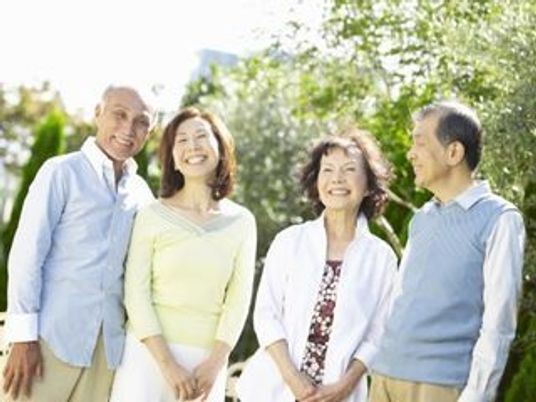 仲間と楽しく話している様子の高齢者夫婦2組。日当たりの良い場所で笑っている様子