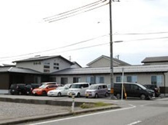２階建ての建物は住宅地の中にあり、建物の前の駐車スペースにはたくさんの車が止められている。