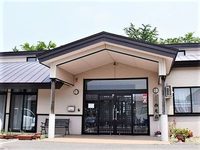 車寄せが付き、花やベンチが置かれた玄関。平屋建ての建物は和の雰囲気。