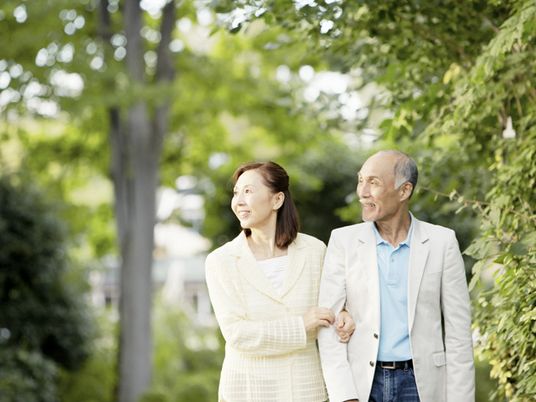 高齢者夫妻が公園を散歩している様子。後ろが豊かな自然に囲まれているのがわかる写真
