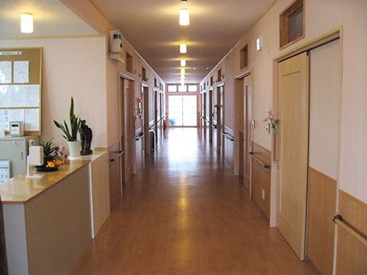 施設内の広めの廊下の様子。個室のドアと壁についた手すりが映っている様子