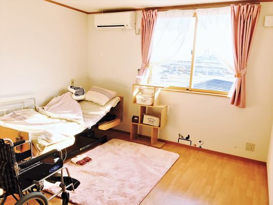 介護用ベッドが置かれたフローリングの居室には大きな窓やエアコンが付いている。