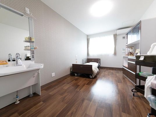 フローリングの部屋には寝具付きのベッドやエアコン、ワイドタイプの洗面所があり、明るい雰囲気。