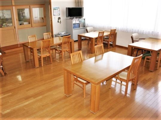 四人掛けのテーブルと椅子が並べられている施設内のリビングスペース