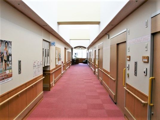 赤いじゅうたんが敷かれた施設の廊下の様子。手すりが取り付けられている様子がわかる