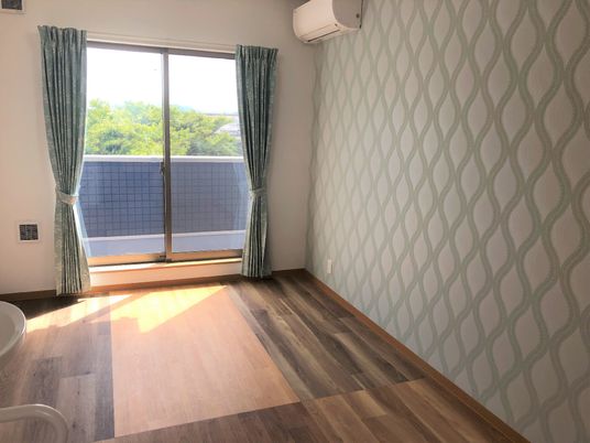 フローリングの部屋にはカーテンが付いた窓があり、エアコンや洗面所も付いている。