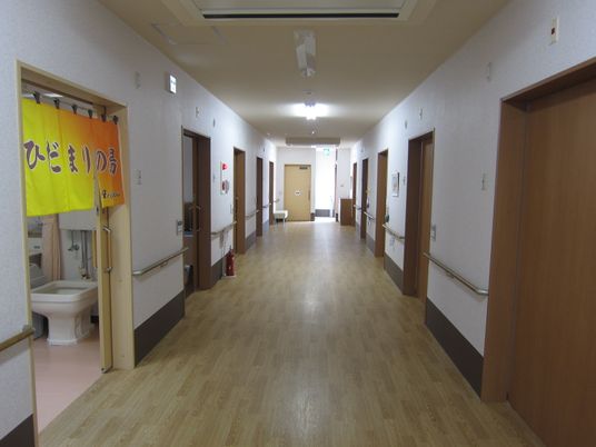 両サイドに手すりが設置された廊下には消火器も。居室が並んでいる。
