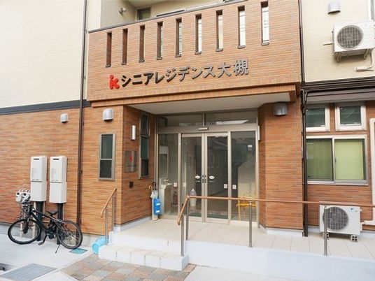 茶色の壁が印象的な施設の外観。スロープがついている施設の入り口