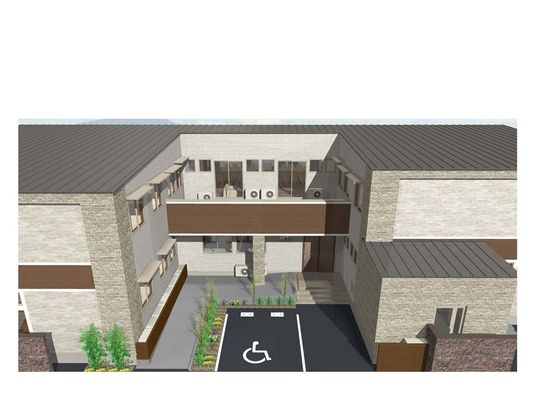 中央に広い駐車場があり、渡り廊下でつながっている茶色い外壁の2階建て建築物