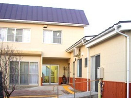 木造２階建ての建物の外観写真。手前に広めの中庭がある様子