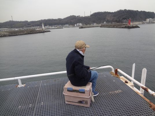 海を背にする釣りをする人