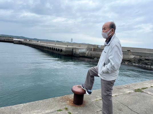 海辺で足を組む高齢者男性