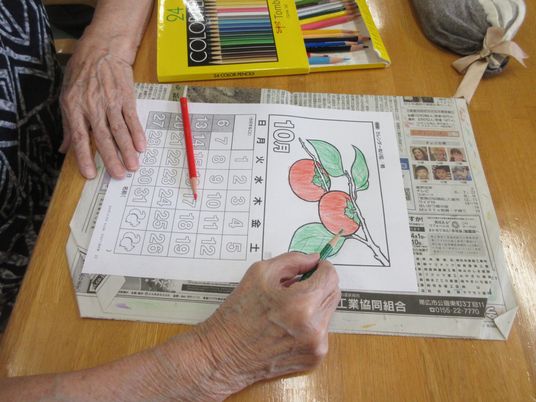 色鉛筆で塗り絵をする人の手  