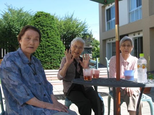 笑顔の利用者三名中庭