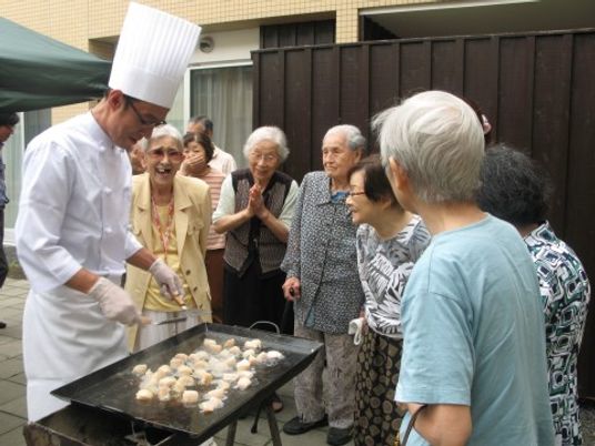 料理するシェフと笑顔の高齢者