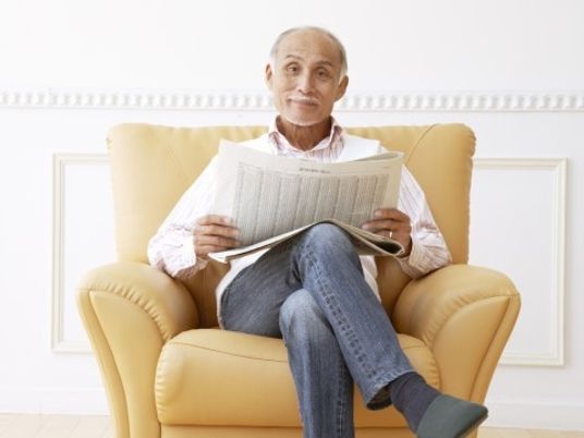 ソファで新聞読む男性