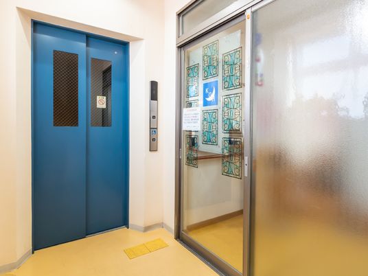 青いエレベーターの扉と掲示物