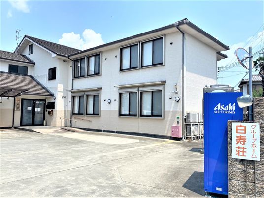 白壁の建物と青い自販機