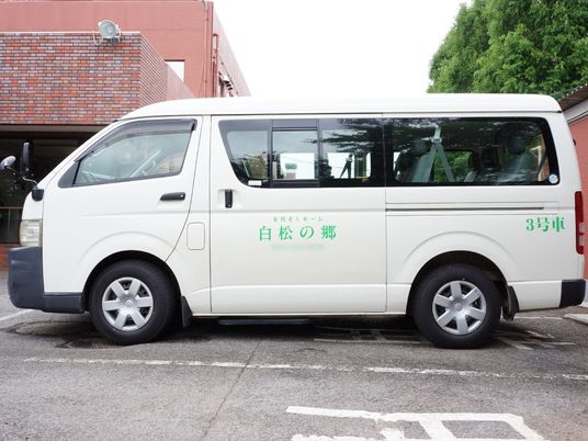 白い送迎車と建物