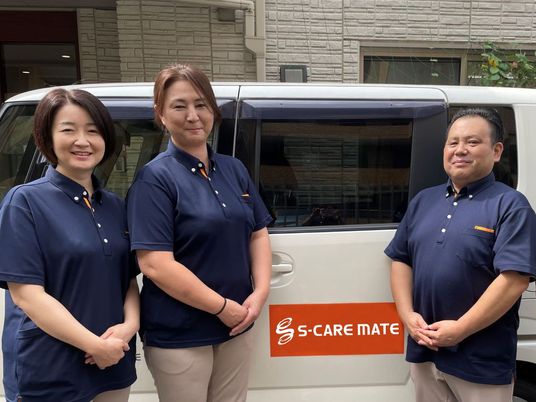 スタッフが立つ送迎車両