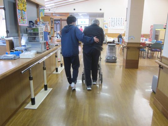 優しい介助を受ける廊下  