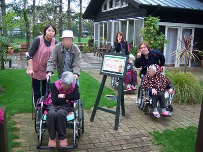 車椅子の使用者と介助者、庭