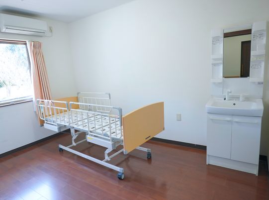 明るい居室のベッドと洗面台