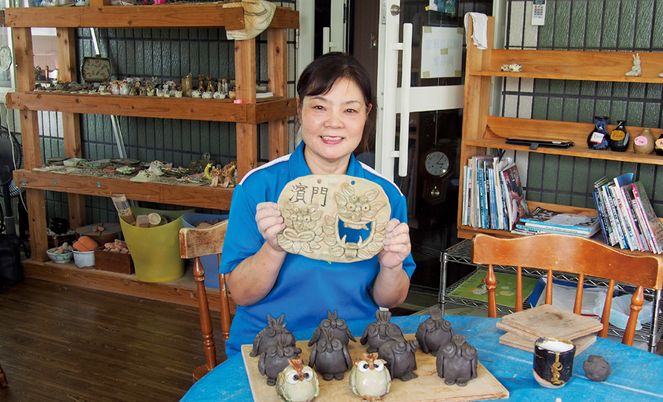 笑顔の女性が陶芸作品を持つ内観