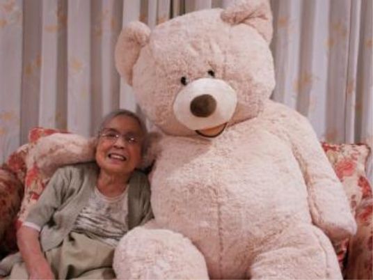 笑顔のおばあさんと大きな熊のぬいぐるみ