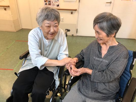 笑顔で手をつなぐ高齢者二人