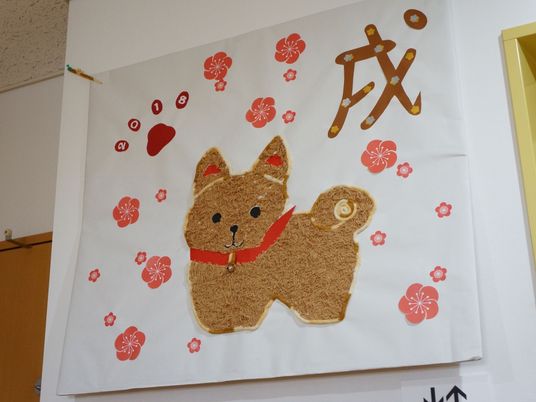犬の壁飾りと紅白の花