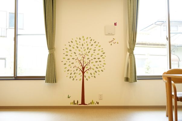 樹木の壁画とカーテンの居室